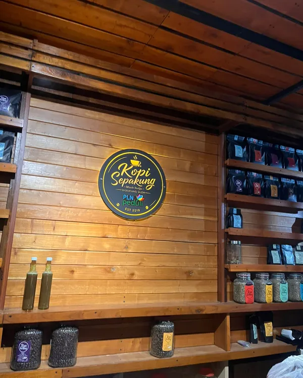 Papan nama Kopi Sepakung Mbah Bedjo dengan kemasan produk kopi tersusun di rak kayu